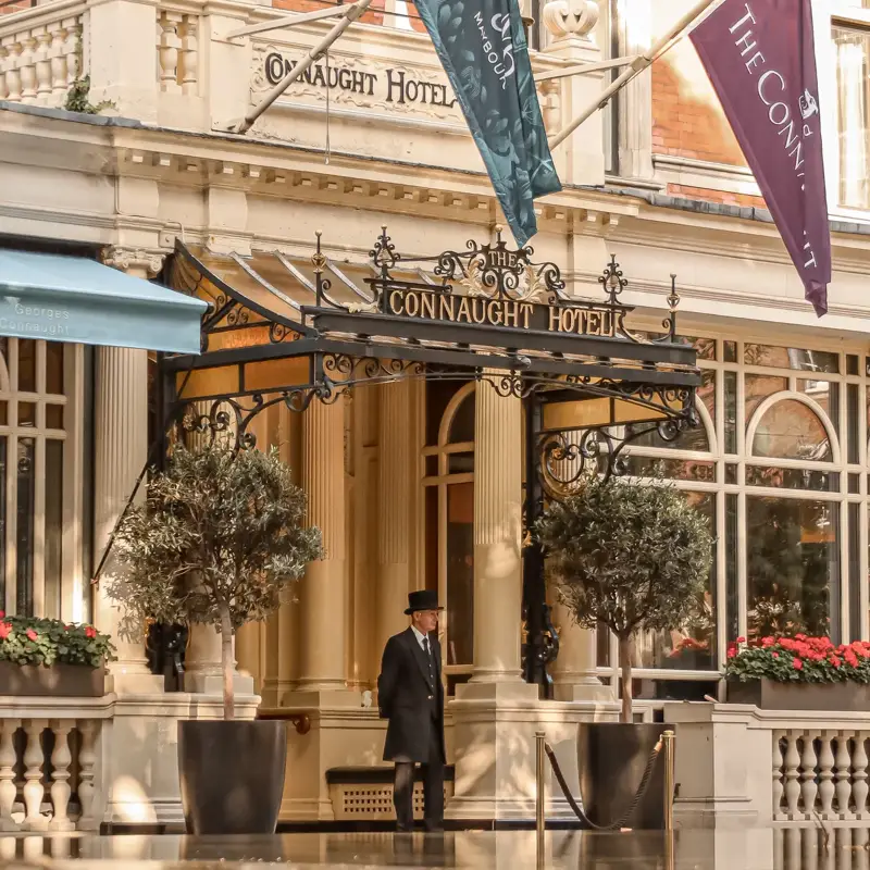 Entrance of The Connaught hotel with its signature canopy and flags above the doorway.