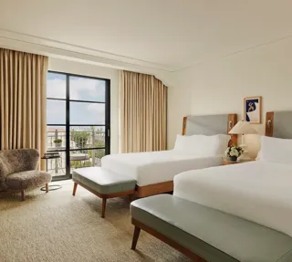 Spacious hotel room with two queen beds, seating area, and balcony doors.