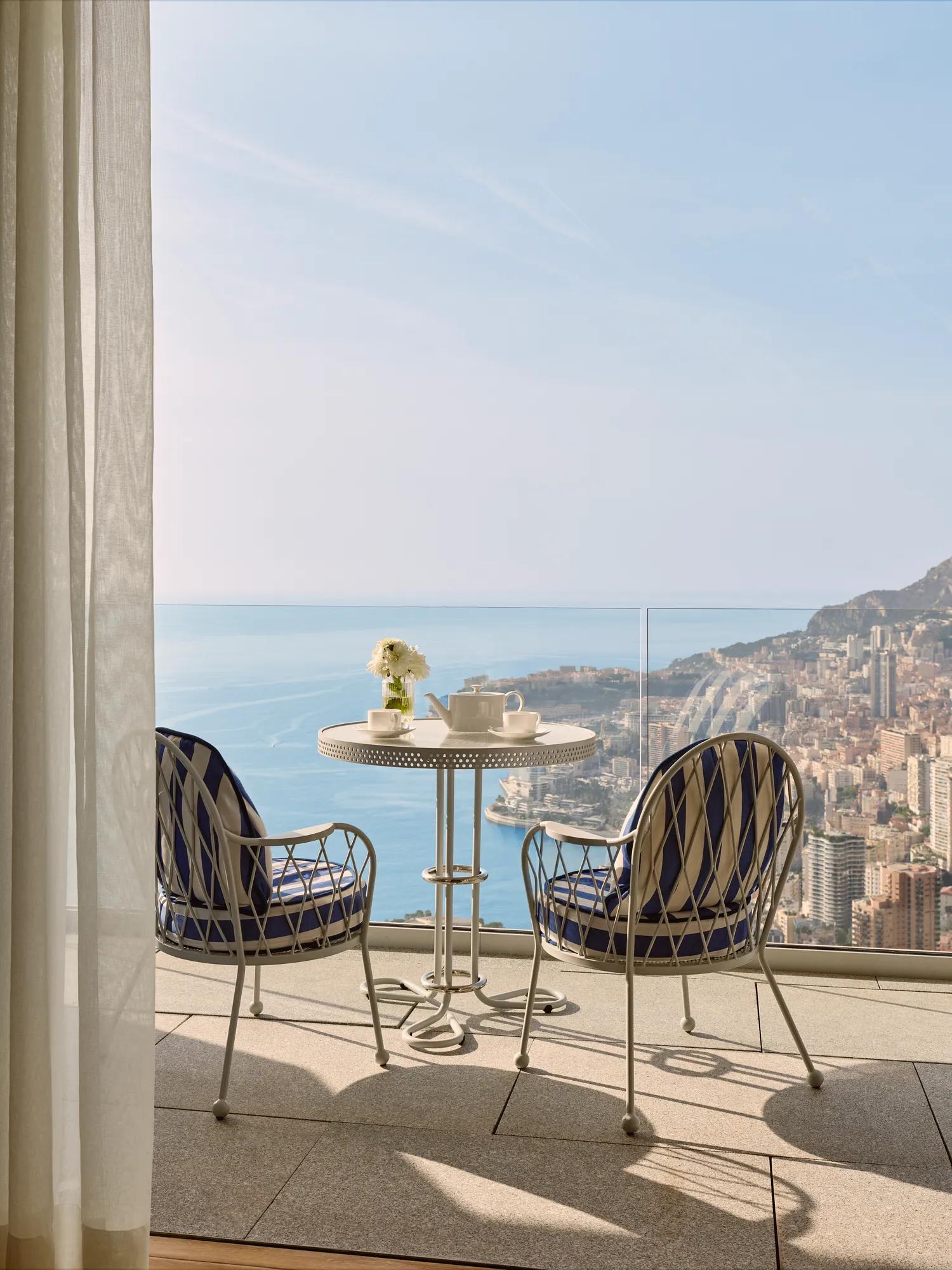 Terrasse privée avec deux fauteuils et table offrant une vue sur la côte de Monaco et la mer.