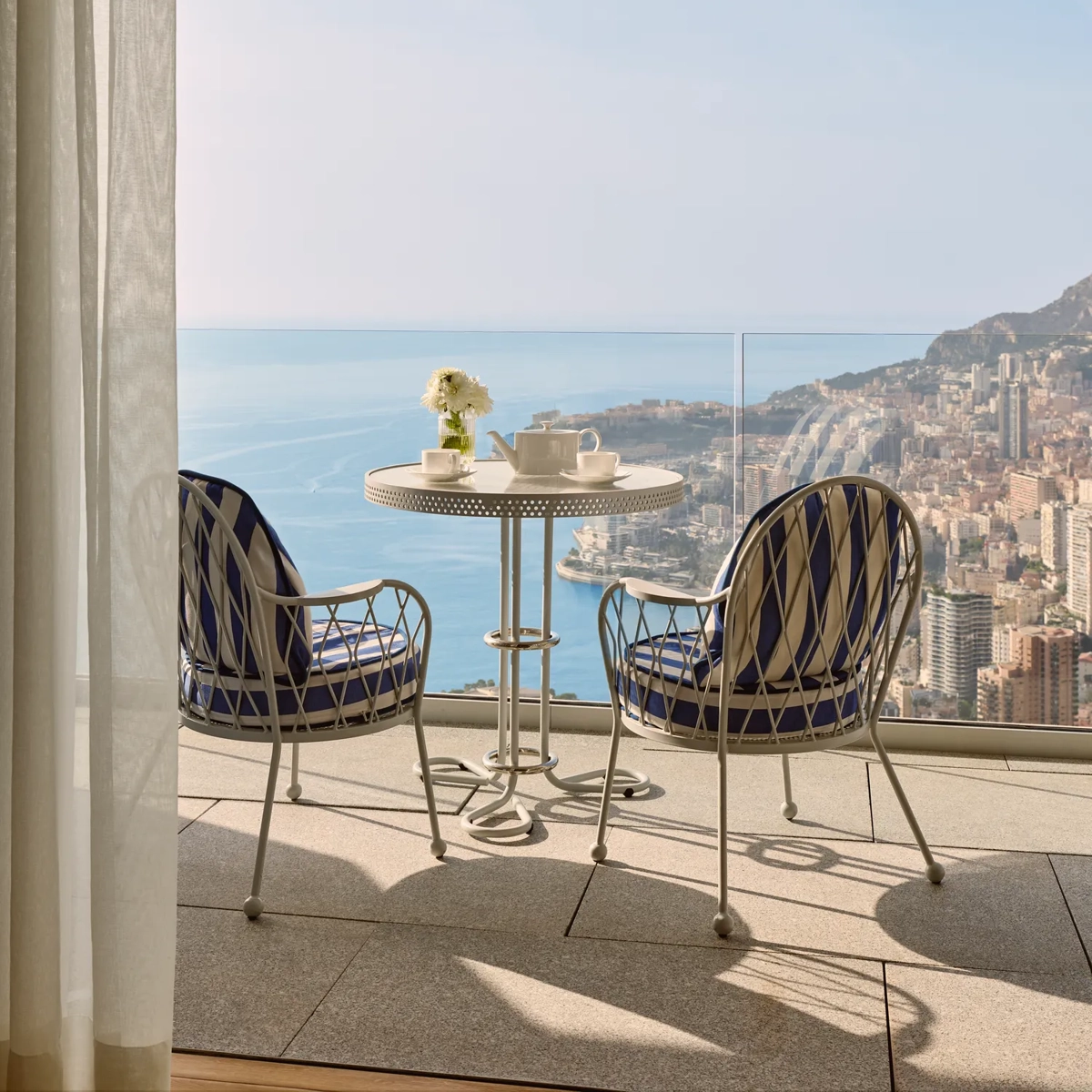 Terrasse privée avec deux fauteuils et table offrant une vue sur la côte de Monaco et la mer.