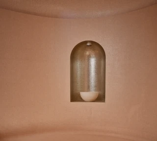 Curved steam room seating with soft lighting, textured walls, and recessed niche lamp creating a warm, calming spa atmosphere.