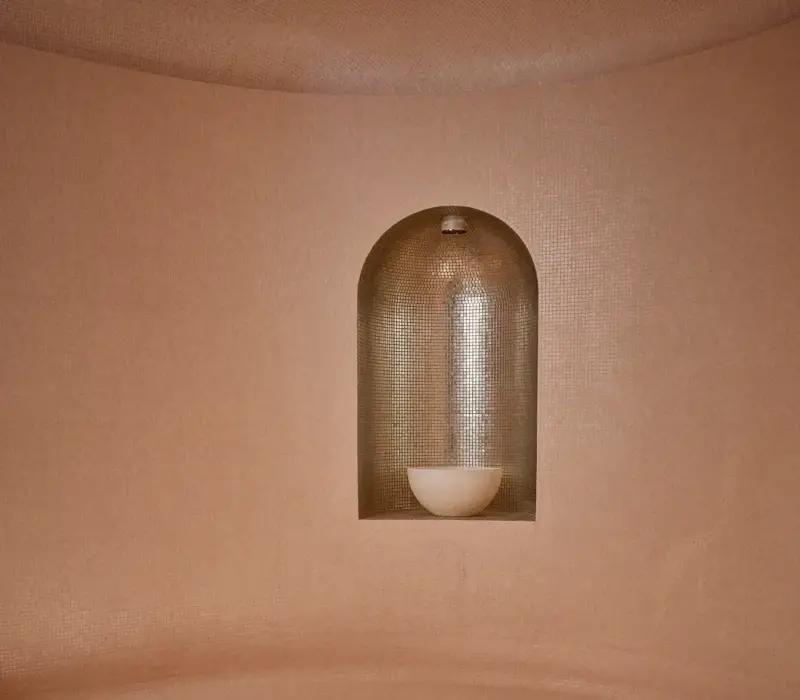 Curved steam room seating with soft lighting, textured walls, and recessed niche lamp creating a warm, calming spa atmosphere.