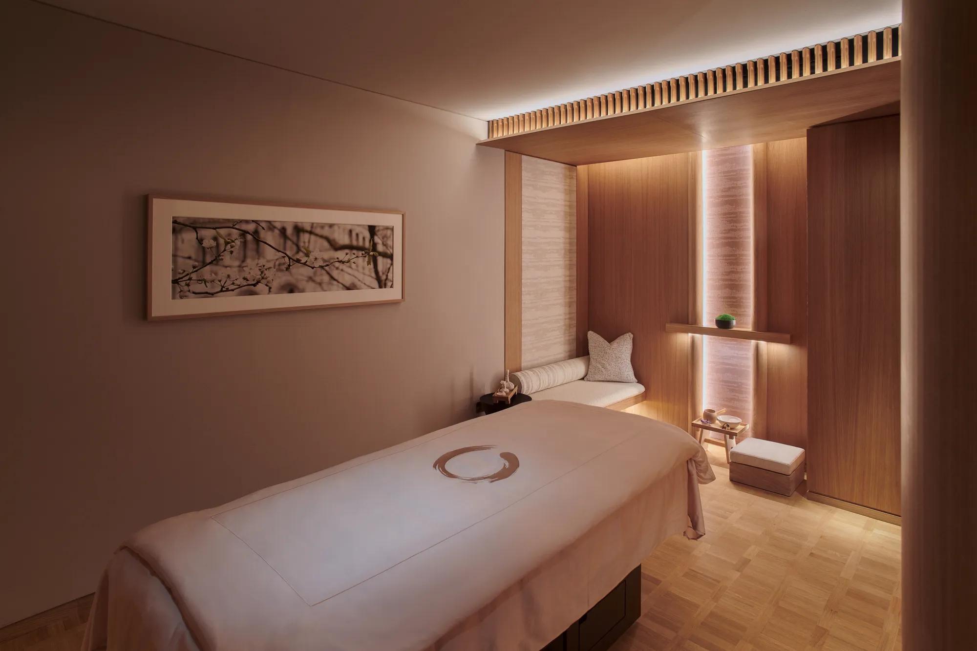 A clean treatment room with a padded table, soft lighting, and neatly arranged medical or wellness equipment.