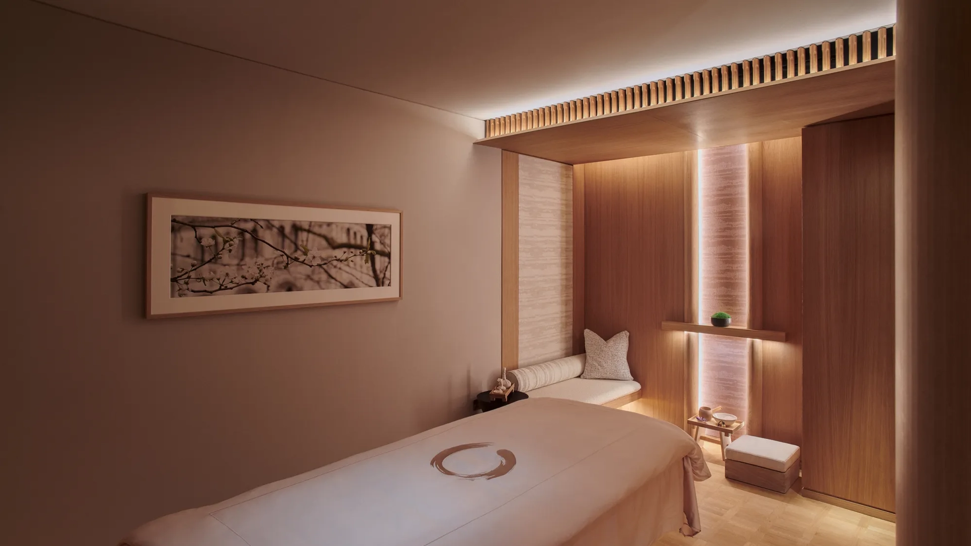 A clean treatment room with a padded table, soft lighting, and neatly arranged medical or wellness equipment.