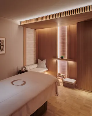 A clean treatment room with a padded table, soft lighting, and neatly arranged medical or wellness equipment.