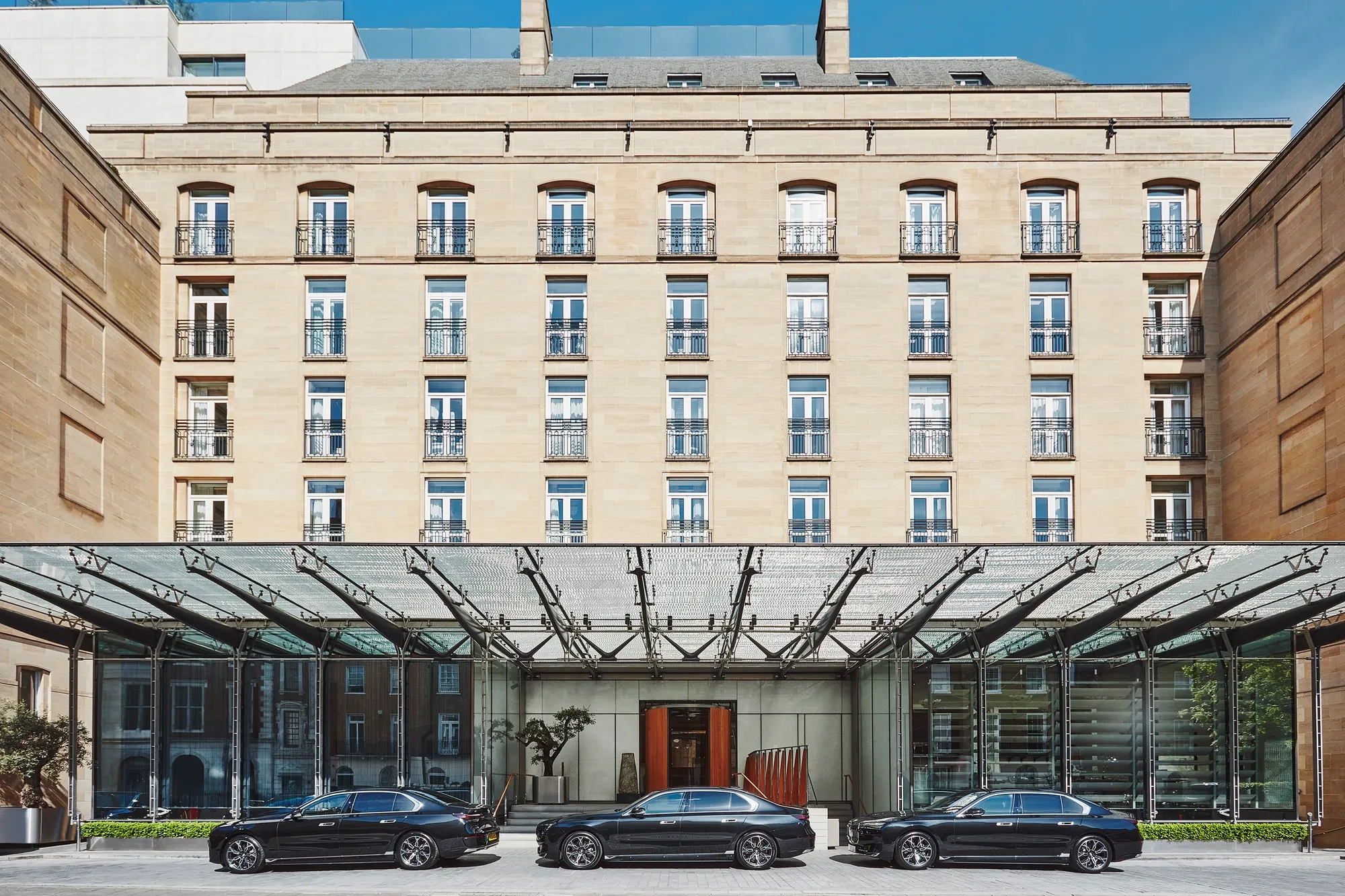 The exterior of The Berkeley hotel with three cars parked in front of the entrance.