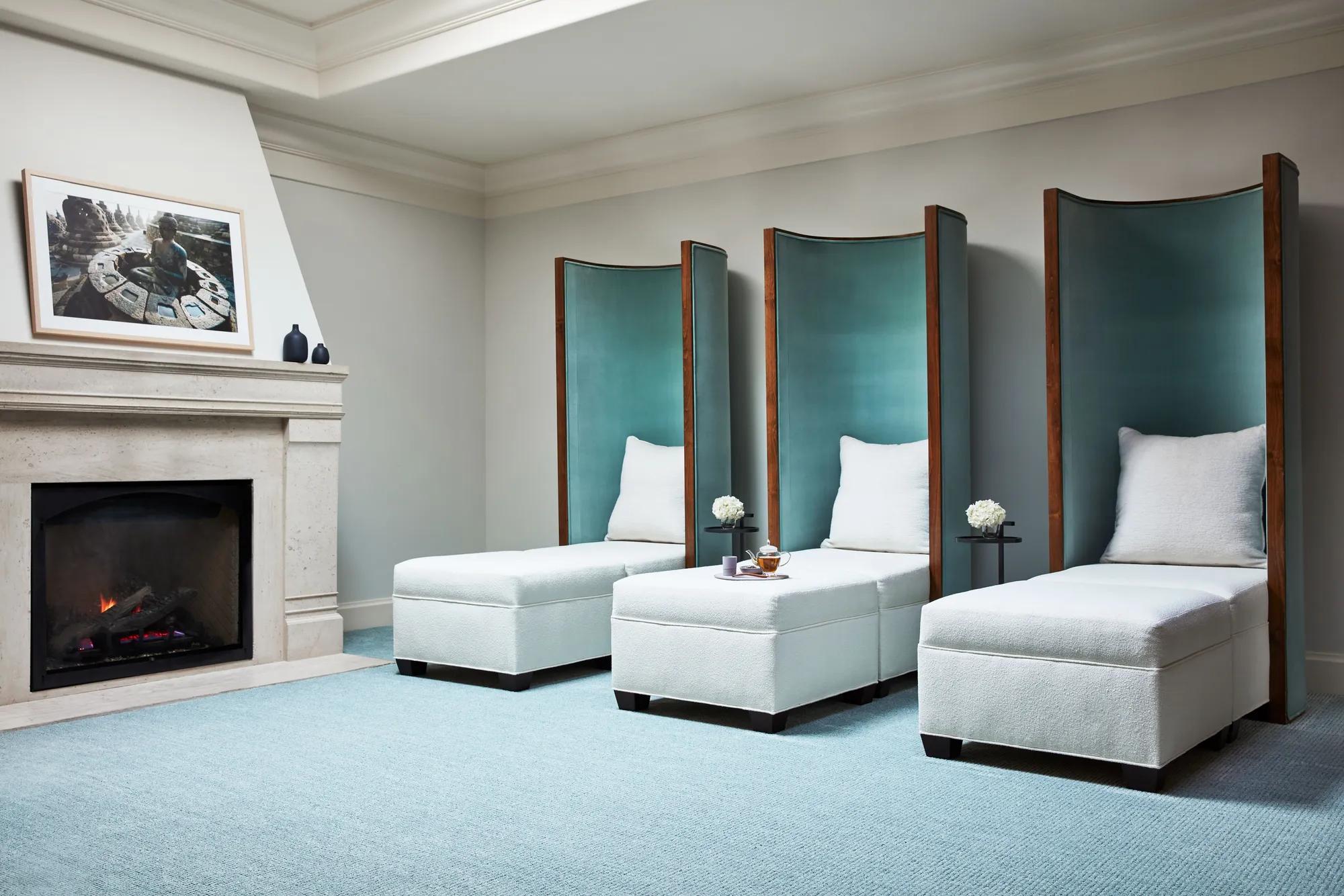 Tranquil relaxation lounge with high-backed daybeds beside fireplace at The Spa at The Maybourne Beverly Hills