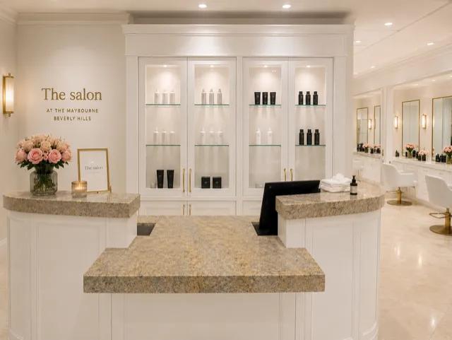 Elegant salon reception at The Maybourne Beverly Hills featuring marble counters, blush roses, product displays, and styling stations.