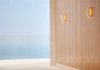Yoga mats laid out in a serene indoor-outdoor space with sea views beyond a glass railing.