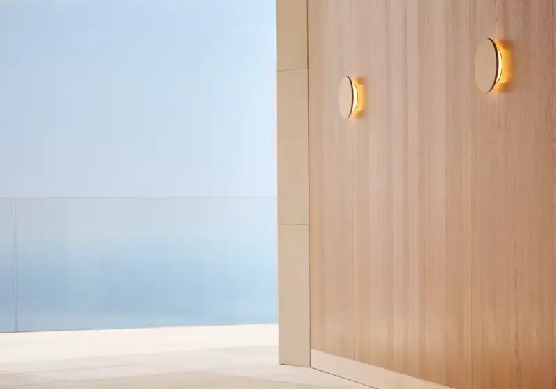 Yoga mats laid out in a serene indoor-outdoor space with sea views beyond a glass railing.