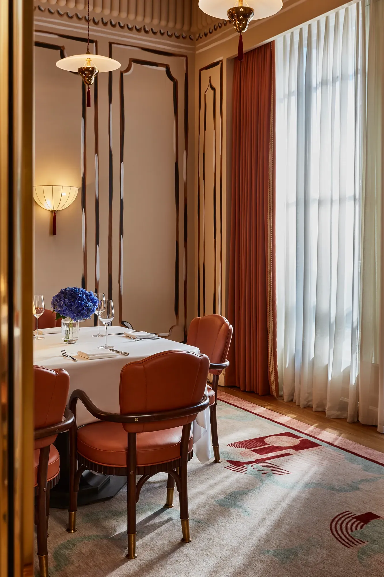 Elegant restaurant booth with white tablecloths, leather chairs, and a large arrangement of hydrangeas.