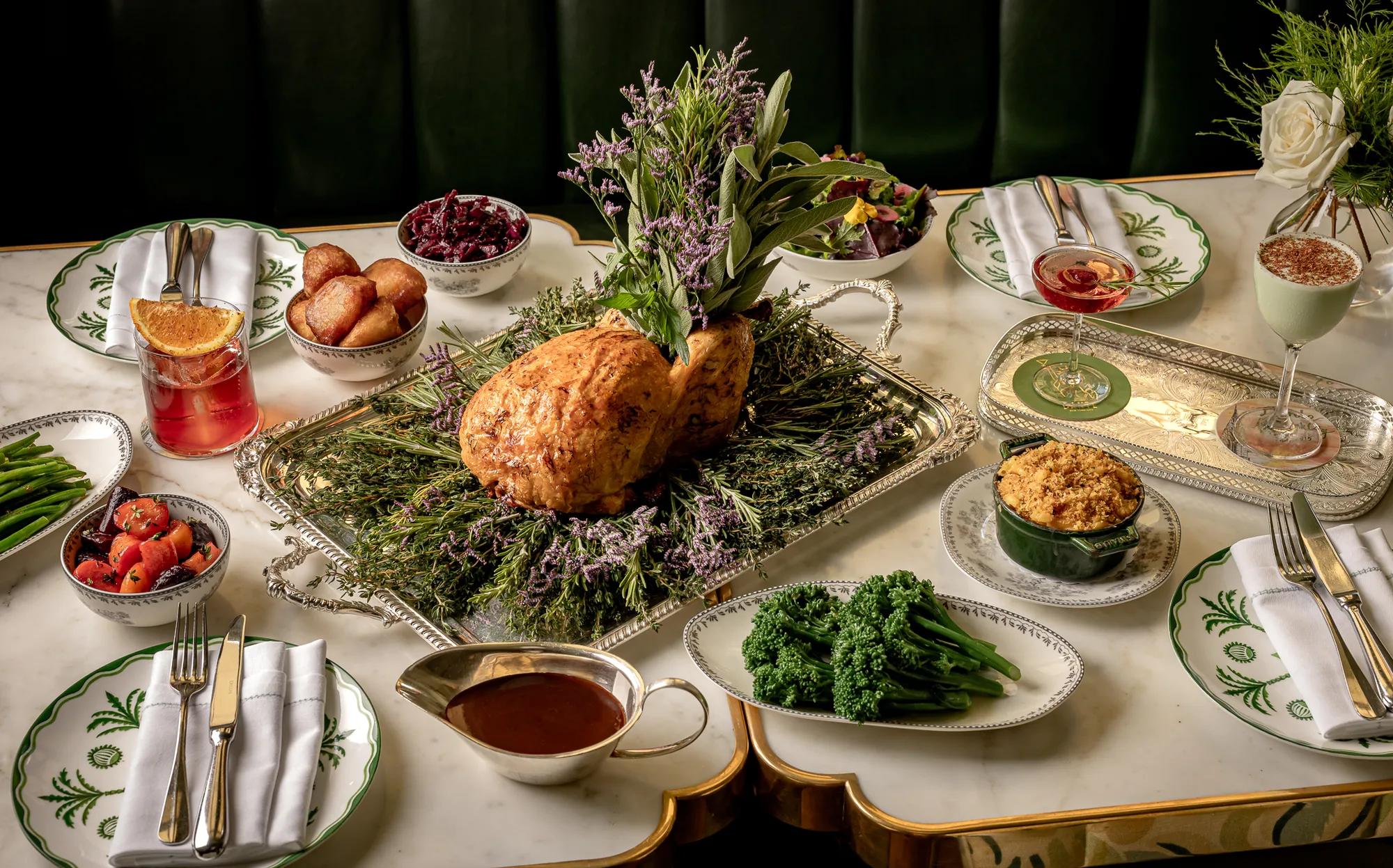 Roast turkey served on a platter with seasonal side dishes, gravy and cocktails arranged on a dining table.