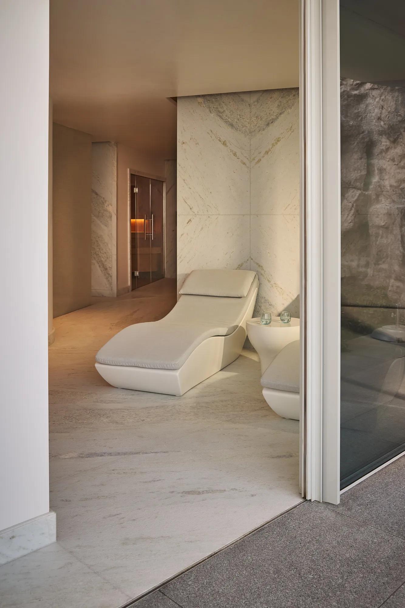 Spa relaxation area with sculpted loungers, marble walls, and soft ambient lighting creating a calm, private retreat.