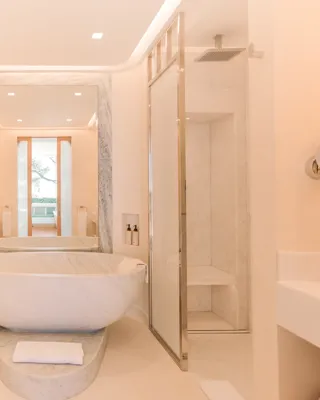Salle de bains élégante en marbre avec baignoire îlot, douche à l’italienne et double vasque.