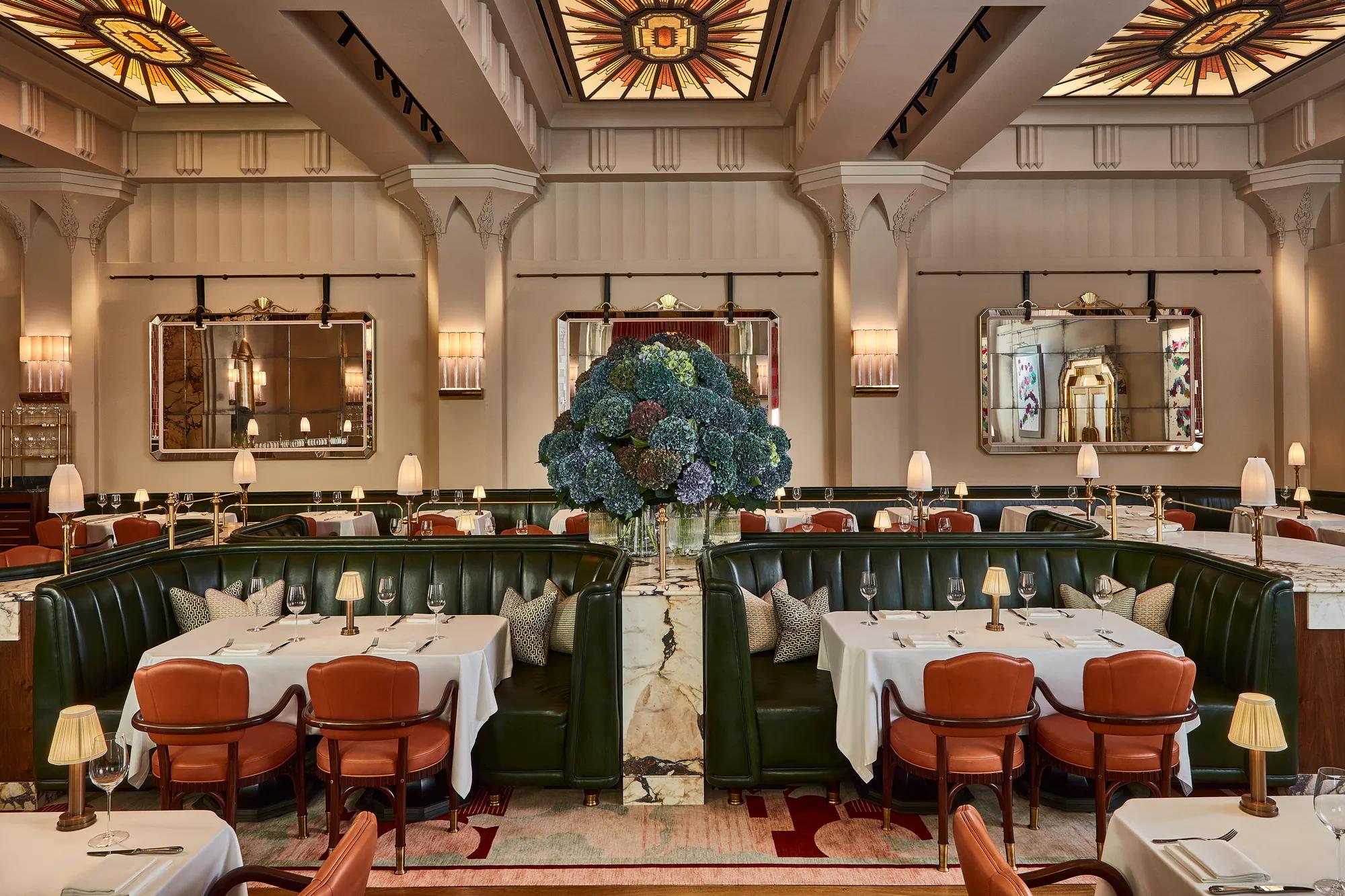 Elegant restaurant with green leather banquettes, art deco ceiling, and a large hydrangea floral centrepiece.