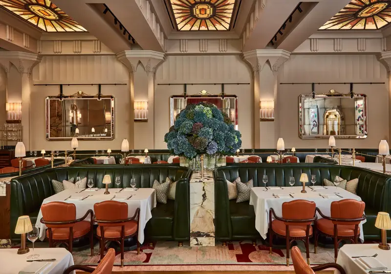 Elegant restaurant with green leather banquettes, art deco ceiling, and a large hydrangea floral centrepiece.