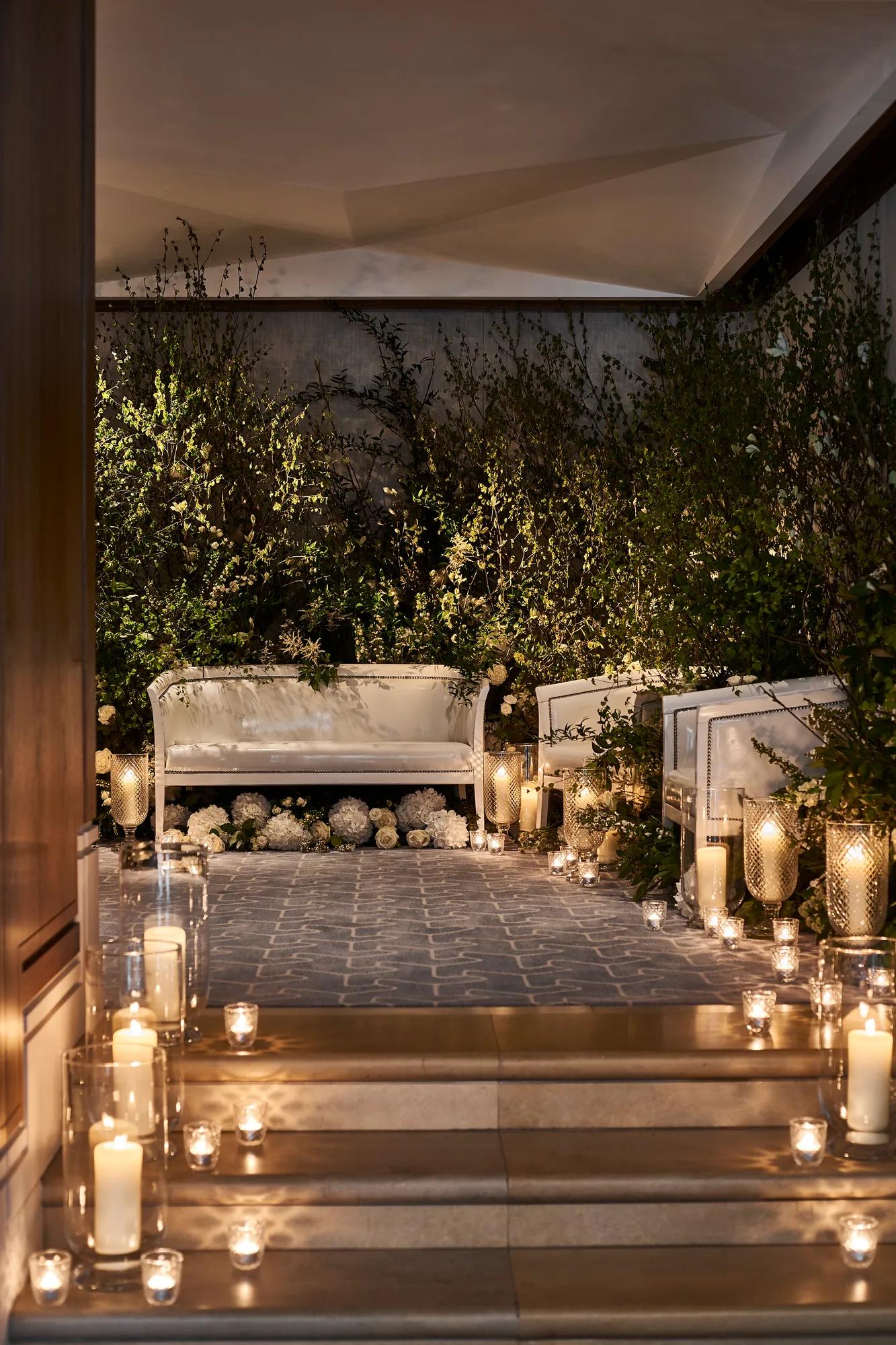 Candlelit seating area with white sofas, greenery, and glowing lanterns creating a romantic ambience