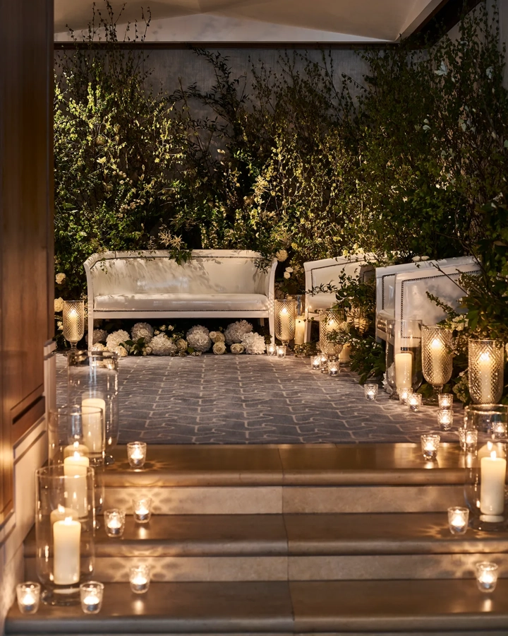 Candlelit seating area with white sofas, greenery, and glowing lanterns creating a romantic ambience