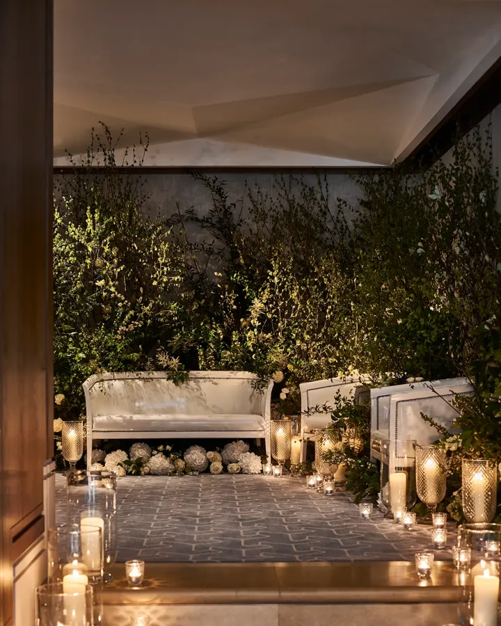 Candlelit seating area with white sofas, greenery, and glowing lanterns creating a romantic ambience