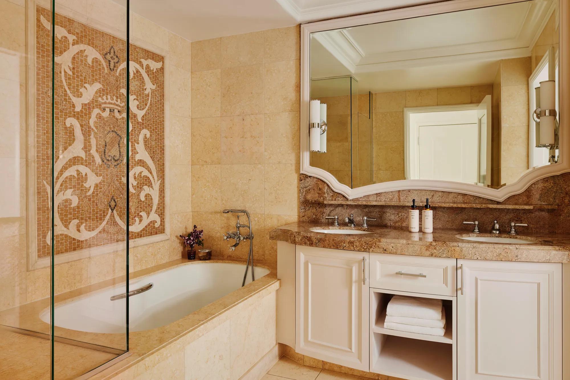 Marble bathroom with double vanity, large mirror, tub and walk-in shower.