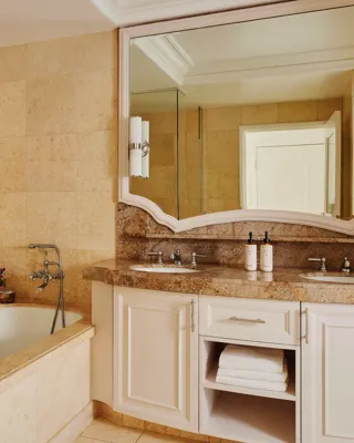 Marble bathroom with double vanity, large mirror, tub and walk-in shower.