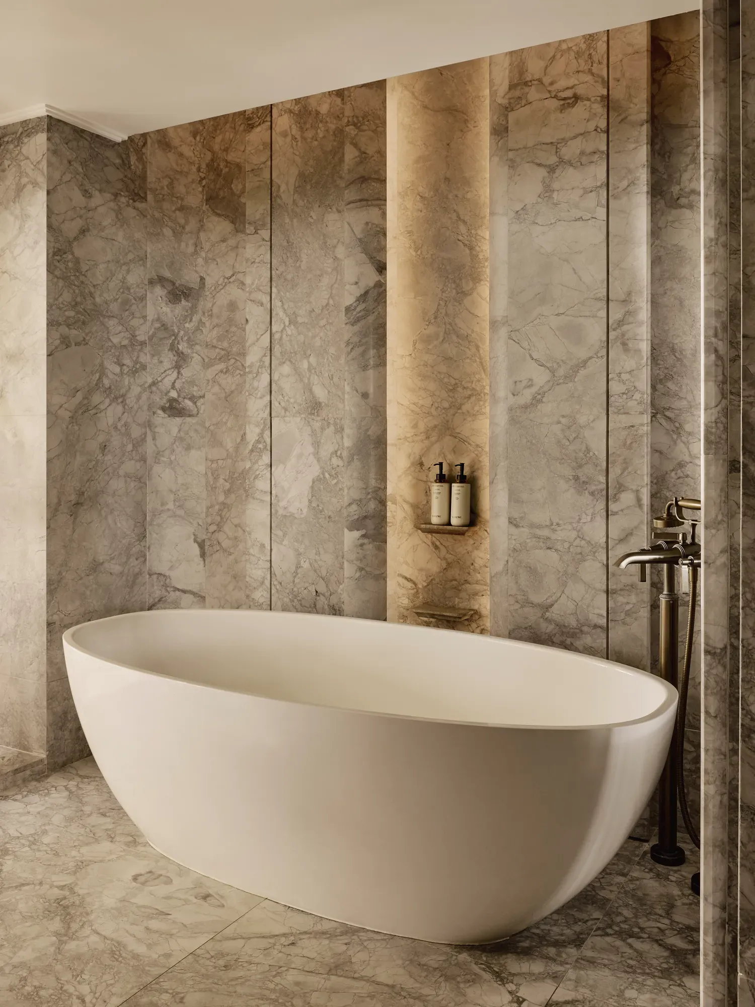 Marble bathroom with freestanding oval bathtub and warm accent lighting