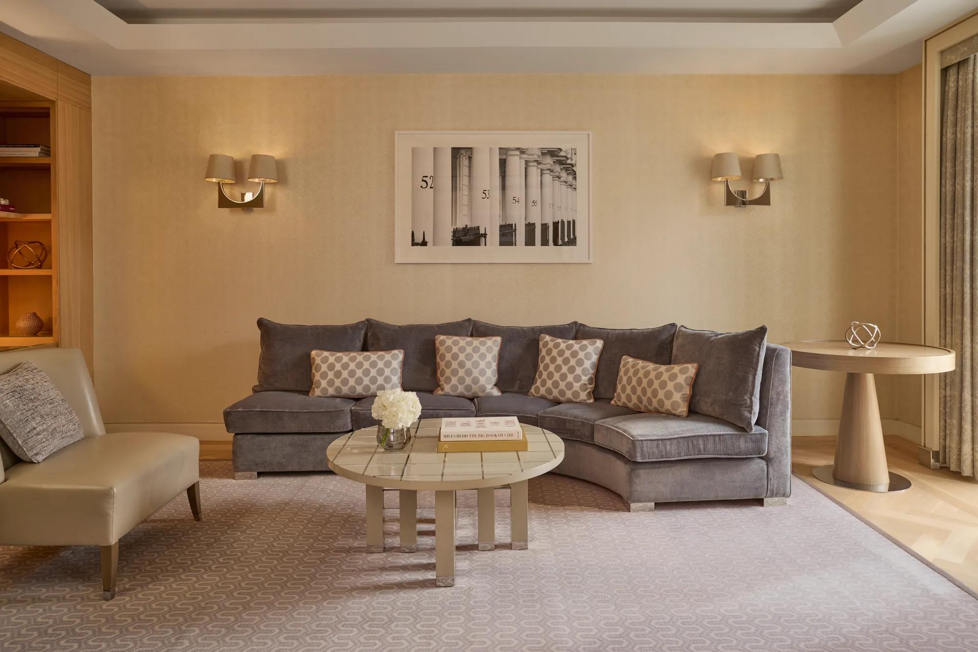 Elegant living room with curved sofa, coffee table, armchair, and soft neutral décor.