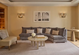 Elegant living room with curved sofa, coffee table, armchair, and soft neutral décor.