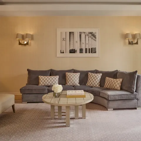 Elegant living room with curved sofa, coffee table, armchair, and soft neutral décor.