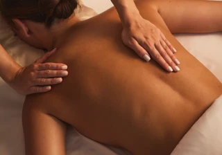 Therapist performing a back massage on a guest lying face down on a treatment bed