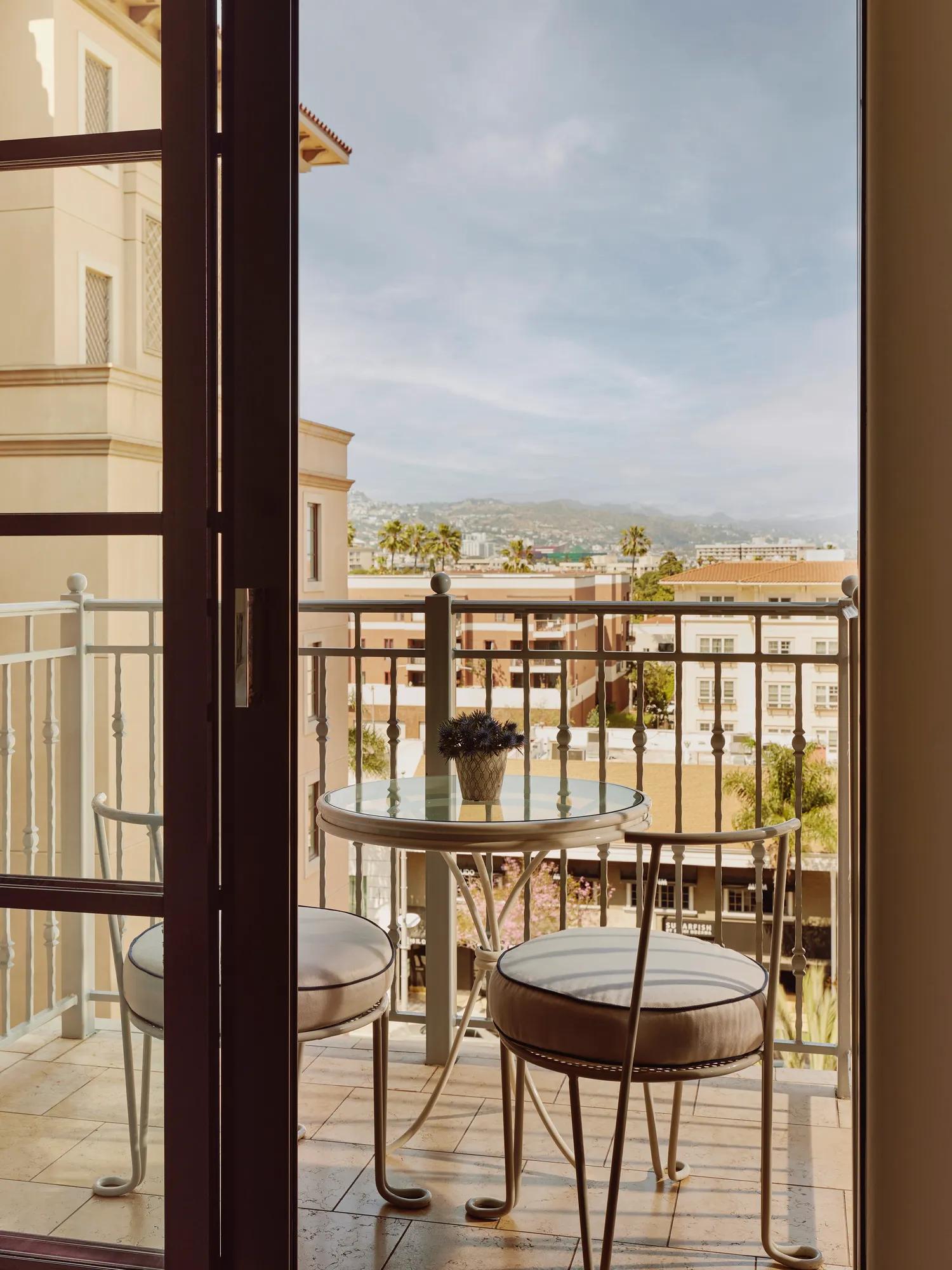 Balcony view with seating area overlooking greenery from a hotel room.