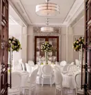 Elegant dining room set with round tables, white chairs, and tall floral centerpieces in soft, natural light.