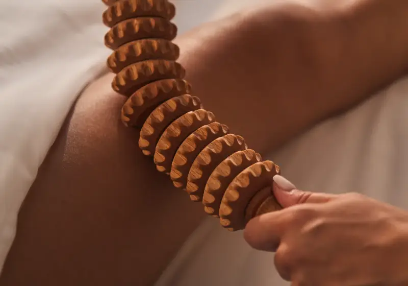 Wooden massage roller applied to leg during spa body treatment.