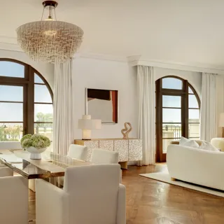 Bright living area in The Maybourne Three-Bed Residence Wilshire with a plush sofa, coffee table, and access to a private balcony.