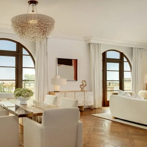 Bright living area in The Maybourne Three-Bed Residence Wilshire with a plush sofa, coffee table, and access to a private balcony.