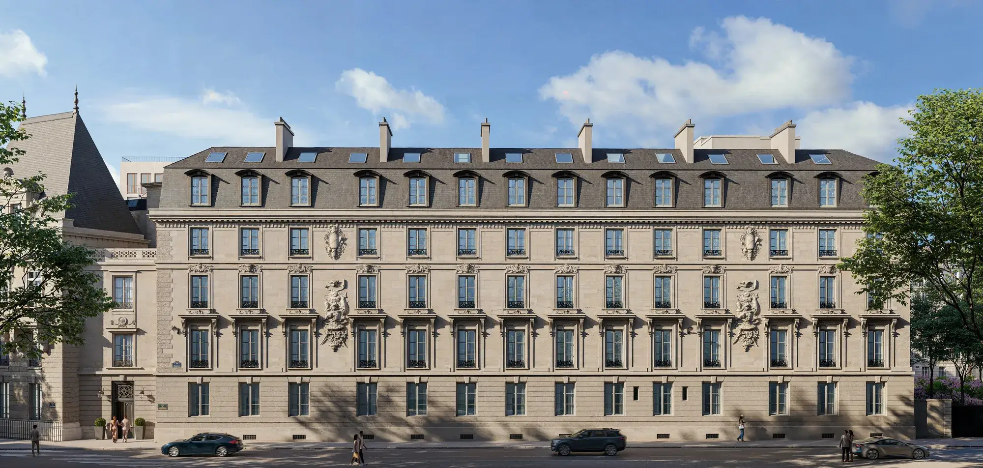 Elegant historic stone building façade with mansard roof, dormer windows, and sculpted details along a tree-lined street