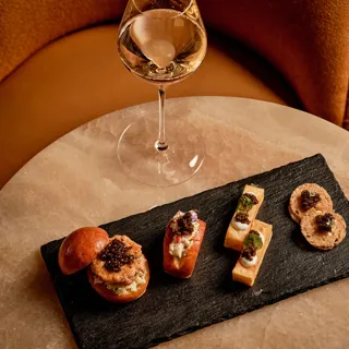 Glass of champagne served with caviar tin, potato chips, and crème fraîche at Maybourne Beverly Hills.