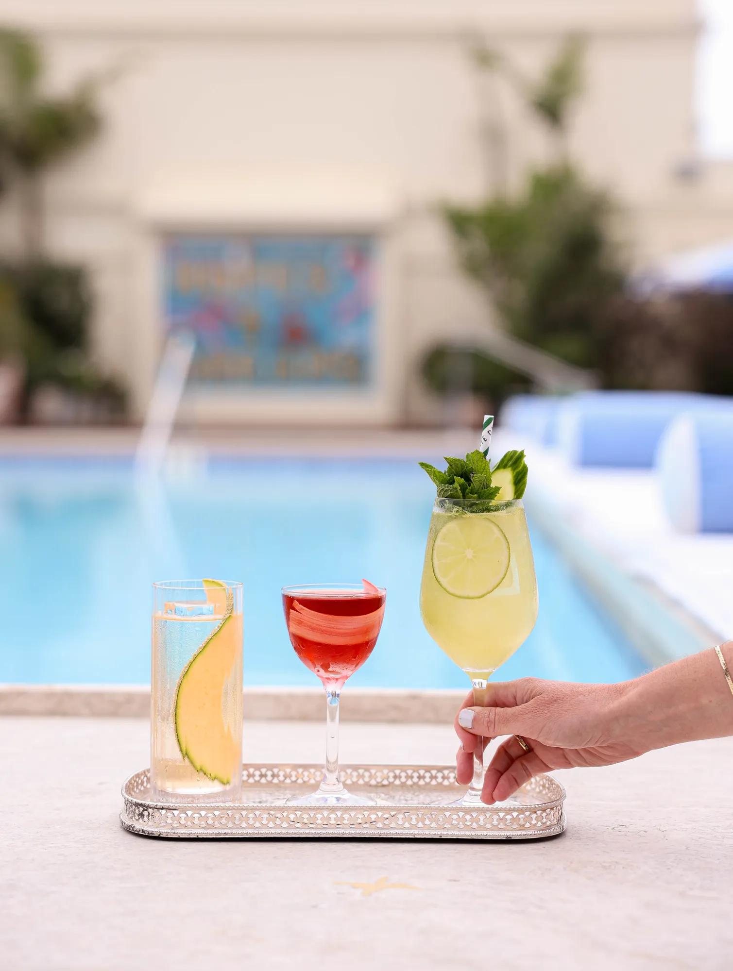 Tray of three colorful cocktails served beside a swimming pool at Dante Poolside.
