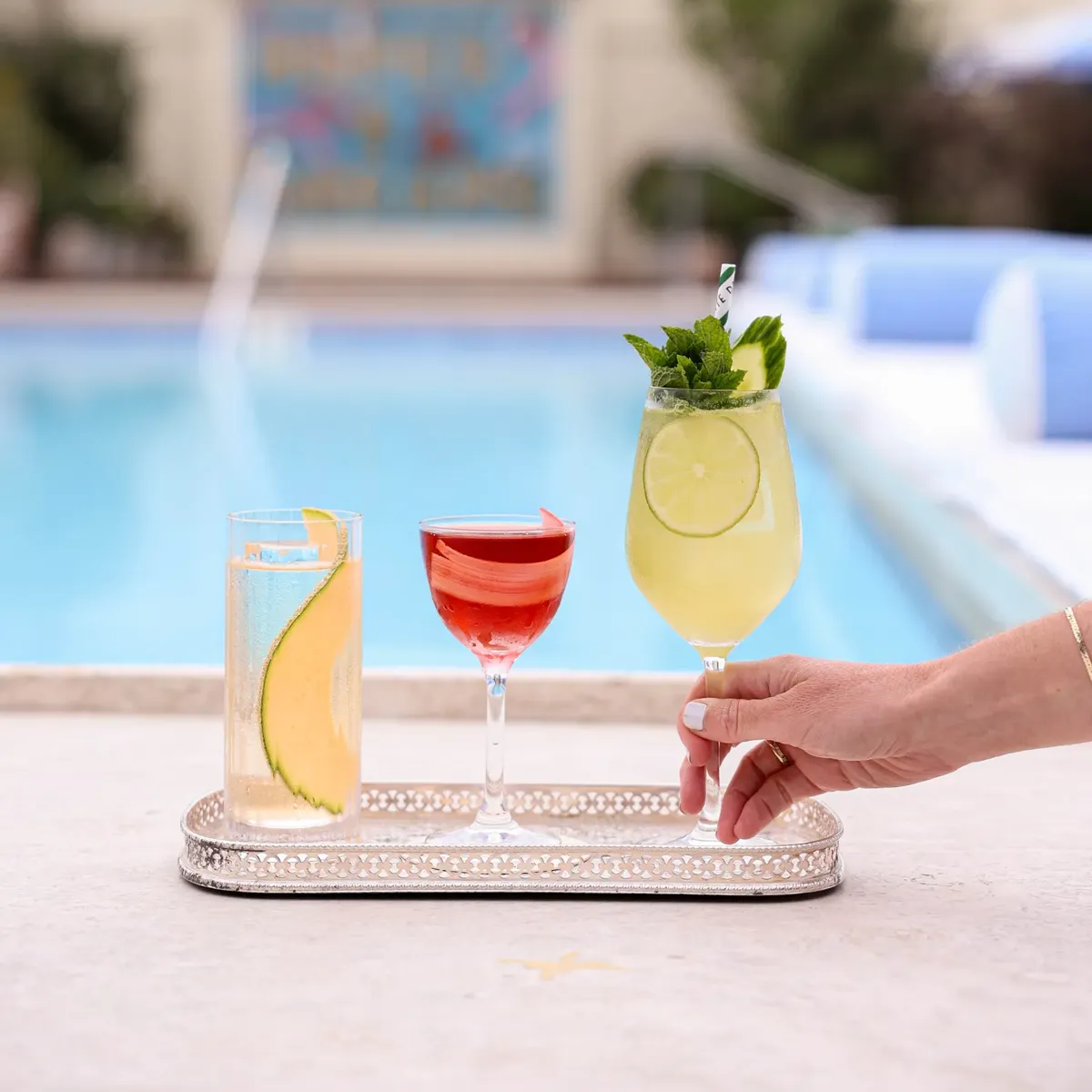 Tray of three colorful cocktails served beside a swimming pool at Dante Poolside.
