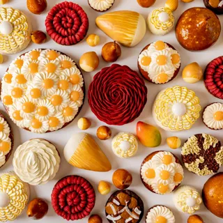 Assorted pastries with mango, pear, citrus and chocolate, decorated with floral cream and spiral patterns in vibrant spring colours