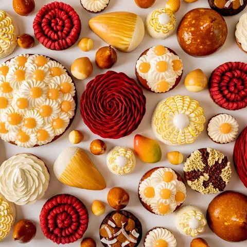 Assorted pastries with mango, pear, citrus and chocolate, decorated with floral cream and spiral patterns in vibrant spring colours