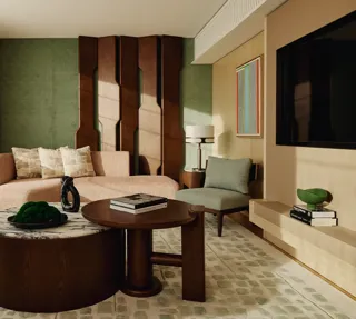 Stylish suite lounge with curved pink sofa, sculptural wall panel, and dual round coffee tables on green-patterned rug.