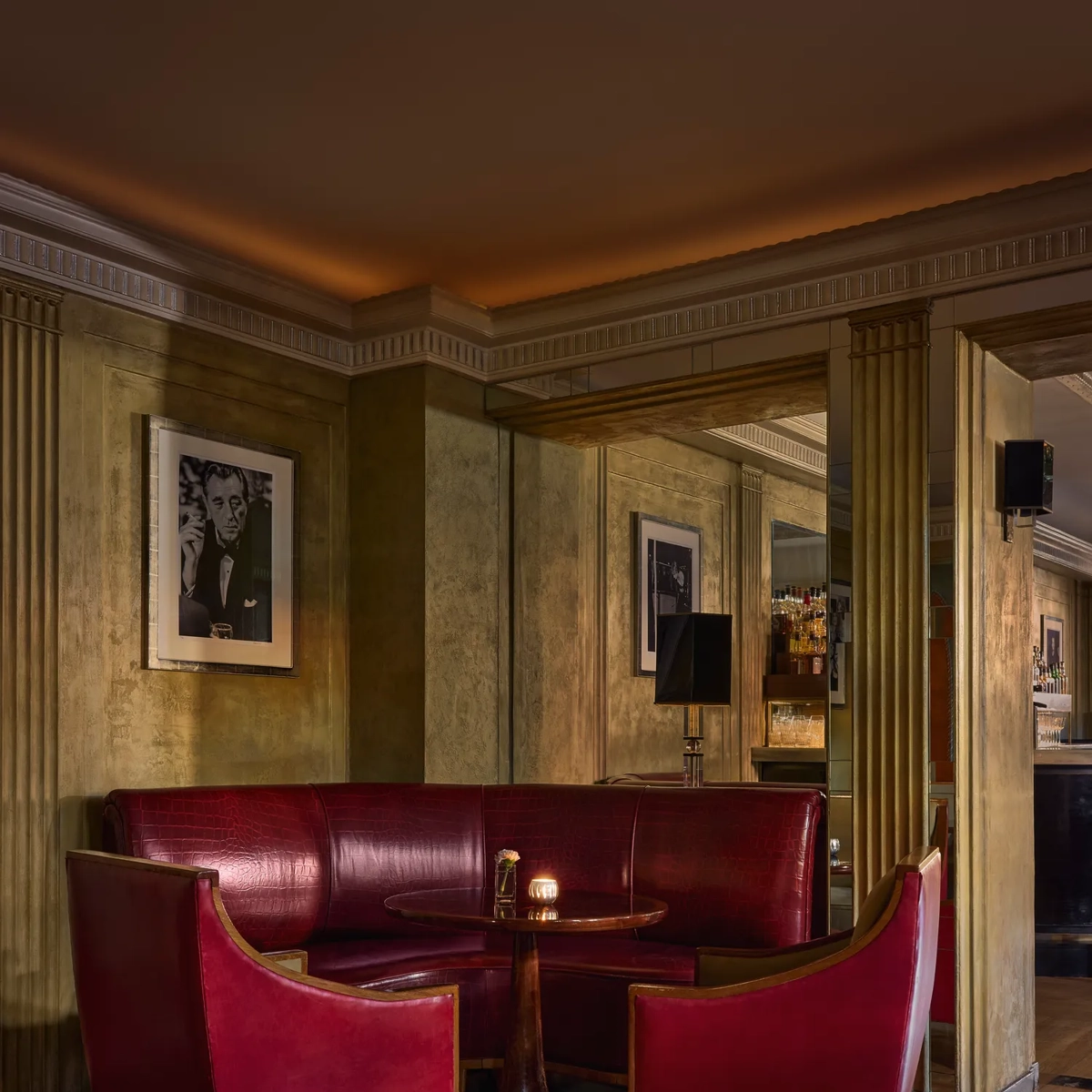 Intimate bar corner at Claridge’s with red leather seating, a small round table, and warm ambient lighting