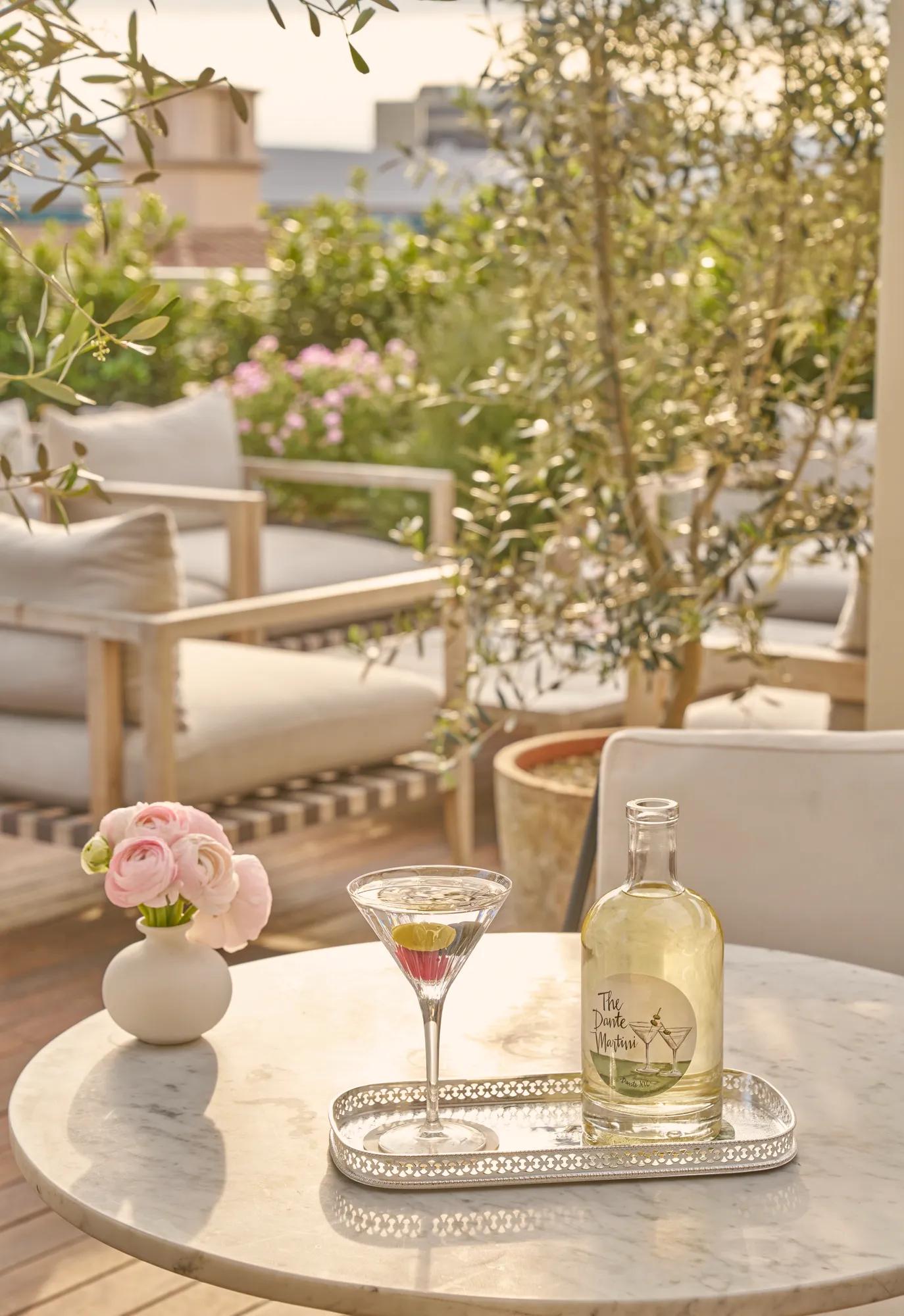 Martini and a bottle on a tray atop a marble table on a sunlit outdoor terrace in Beverly Hills