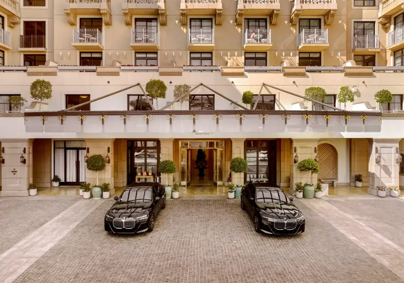 Porte-cochère at The Maybourne Beverly Hills with two black BMW sedan cars at the entry.