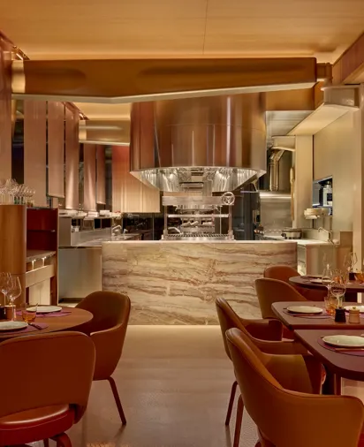 An empty restaurant with neatly arranged tables, chairs pushed in, and soft lighting illuminating the quiet space.
