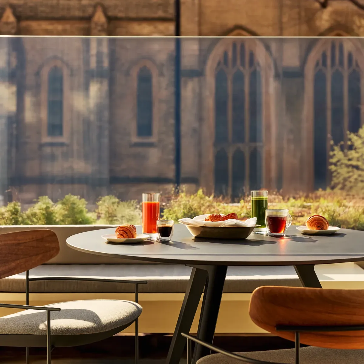 Terrace dining table with breakfast, chairs, and view of gothic church and green trees.