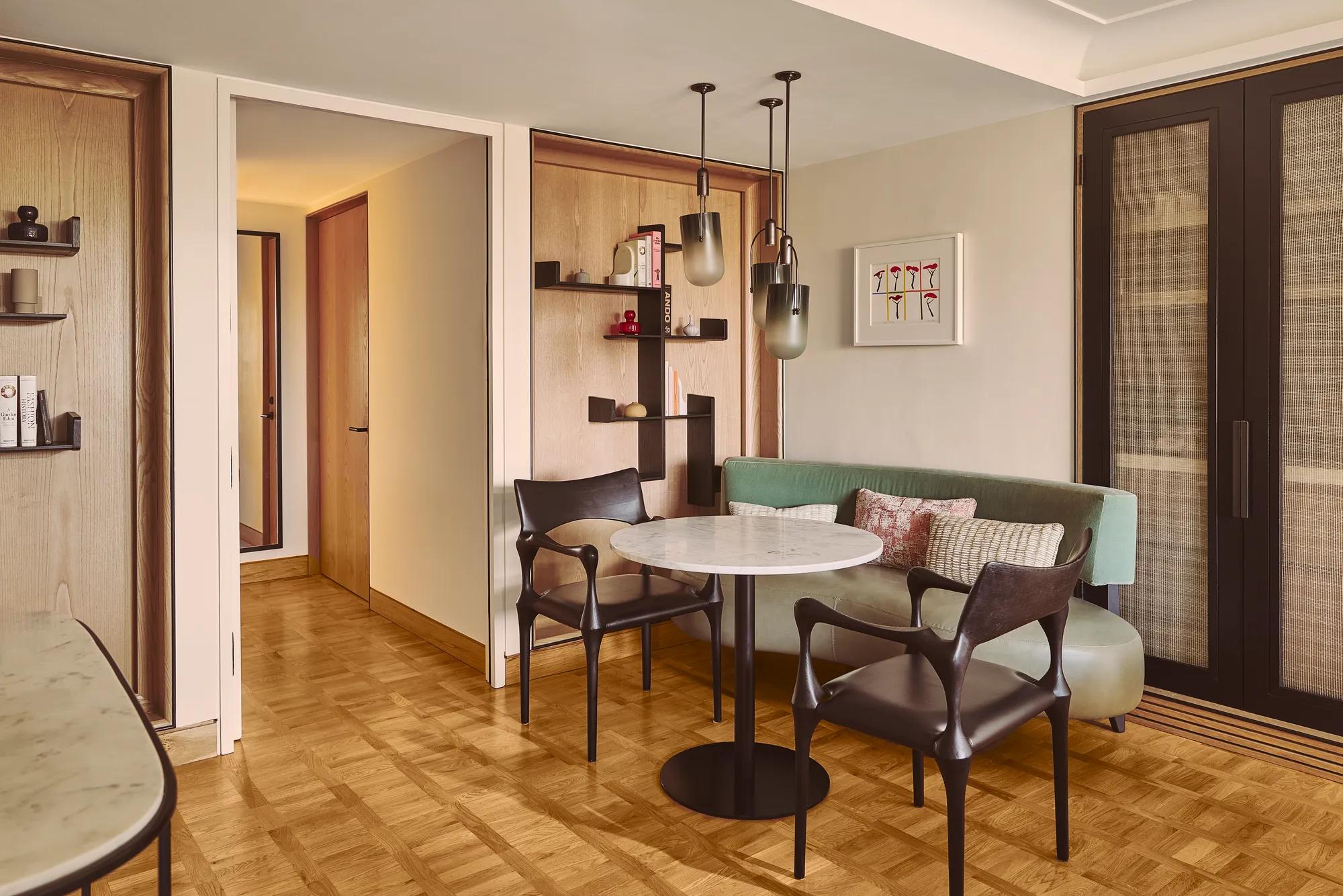 Dining nook with marble table, two chairs, built-in bench seating, shelving, and pendant lights.
