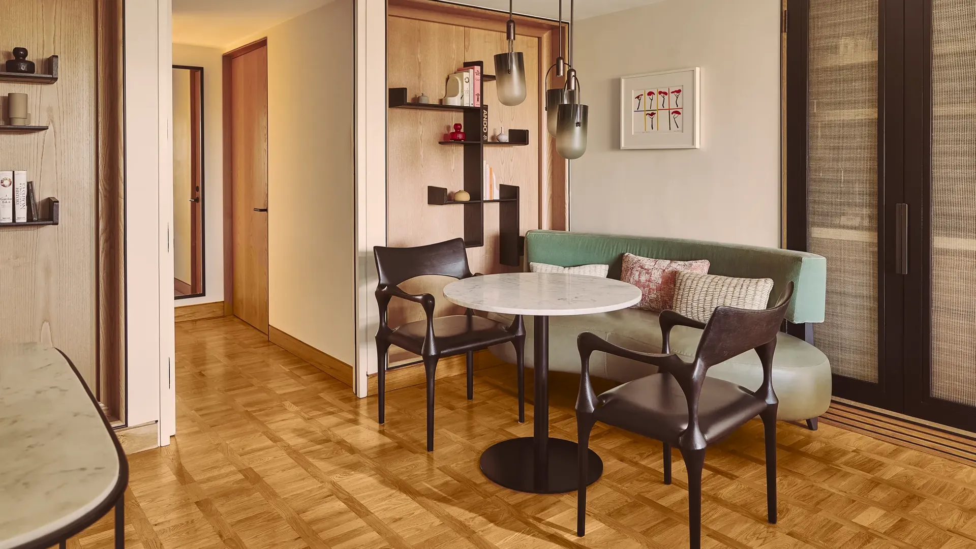 Dining nook with marble table, two chairs, built-in bench seating, shelving, and pendant lights.