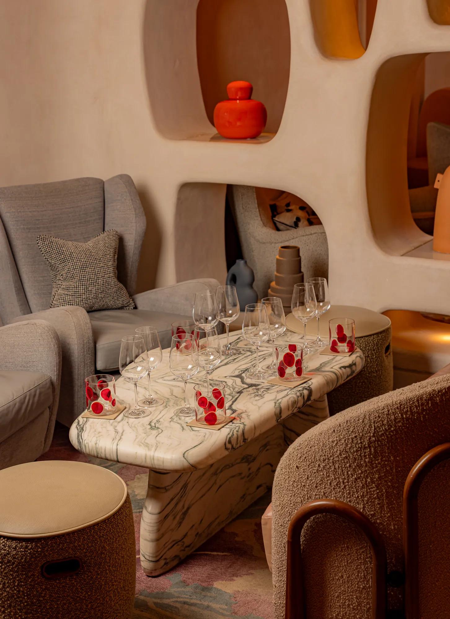 Marble coffee table set with wine glasses and small desserts in a stylish lounge seating area.